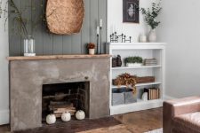 a modern farmhouse living room with a grey beadboard wall and a concrete fireplace with firewood and pumpkins