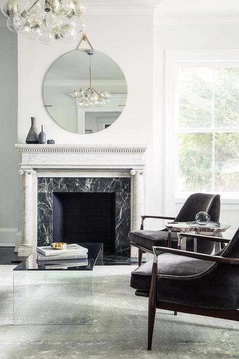 a modern luxurious living room in a monochromatic color scheme, with a fireplace clad with black marble and a white marble mantel
