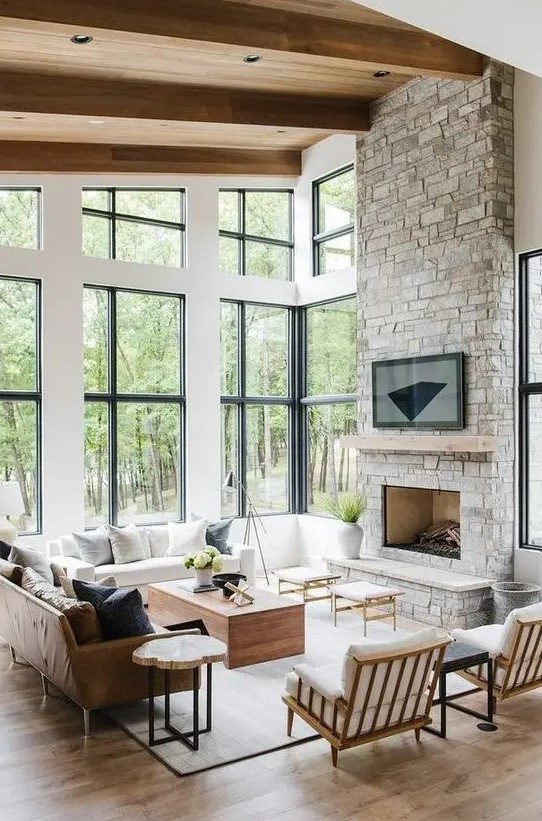 a modern rustic living room with a stone clad fireplace, wooden furniture and a leather sofa plus comfy wooden chairs