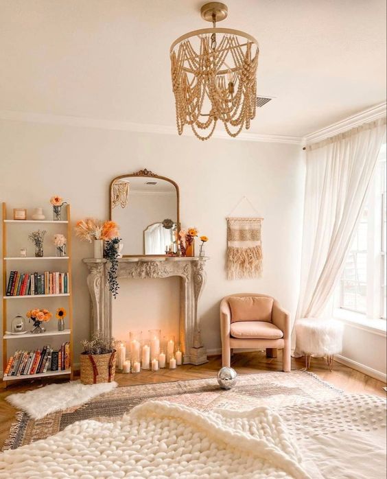 a neutral boho living room with a French fireplace and candles, a blush chair, a bead chandelier and some rugs
