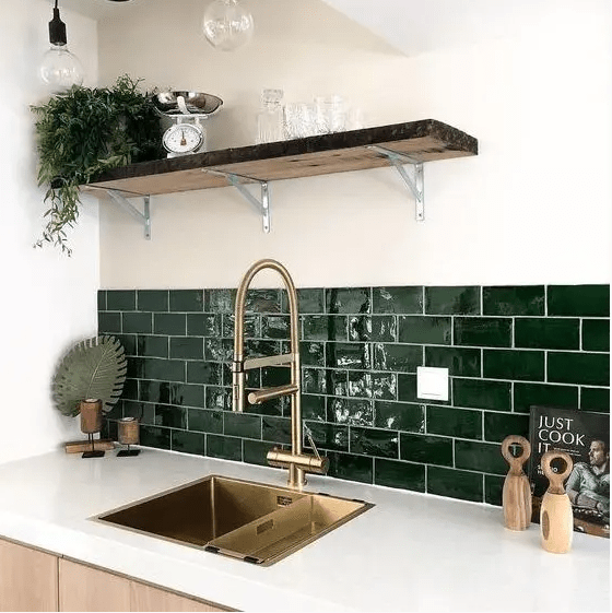 a neutral contemporary kitchen with white countertops and hunter green subway tiles plus gold fixtures for a more elegant look