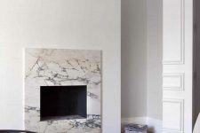 a neutral minimalist living room with a non-working fireplace clad with white marble for a chic and cool touch