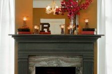 a non-working fireplace with candles, books, bold blooms and a monogram on the mantel is lovely