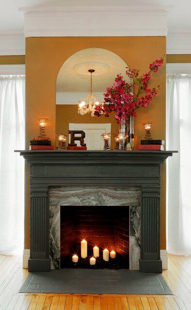 A non working fireplace with candles, books, bold blooms and a monogram on the mantel is lovely