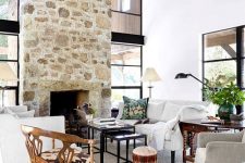 a refined vintage farmhouse bedroom with a stone fireplace, eclectic furniture and neutral textiles