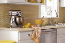 a retro-inspired kitchen with white cabinets, a yellow penny tile backsplash and yellow painted niches
