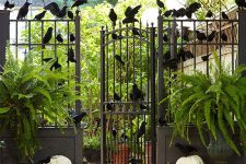 a rustic Halloween gate with tons of blackbirds, pumpkins on the ground and ferns in planters is easy to arrange