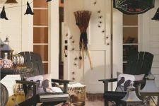 a rustic Halloween porch with witches’ hats, natural pumpkins, candle lanterns, a broom and cool pillows