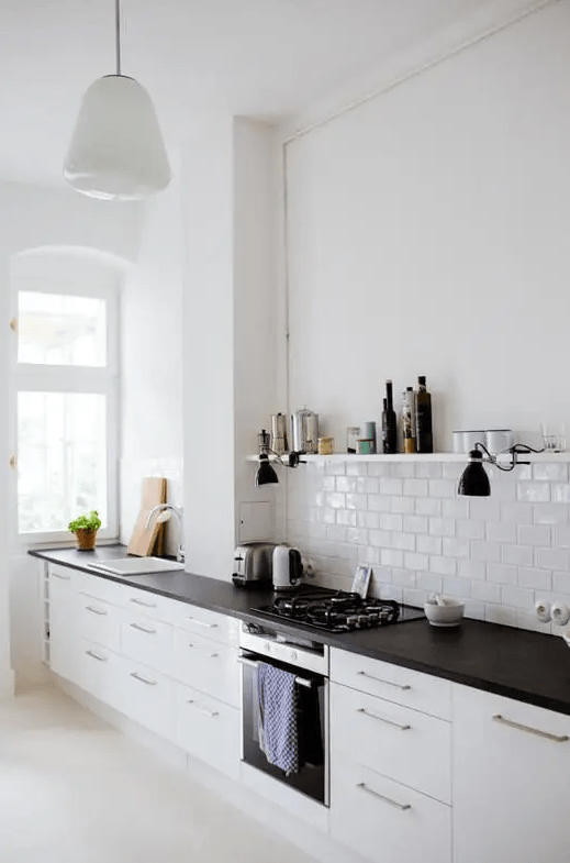 a serene Scandinavian kitchen with only lower cabinets and dark butcherblock countertops, a white subway tile backsplash and a shelf