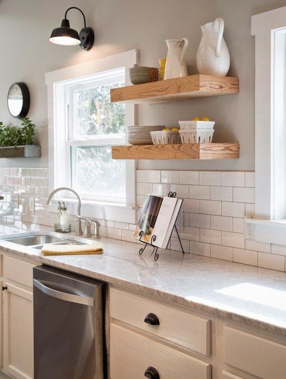 a serene kitchen with grey walls, white cabinets, stained shelves, grey countertops and black touches