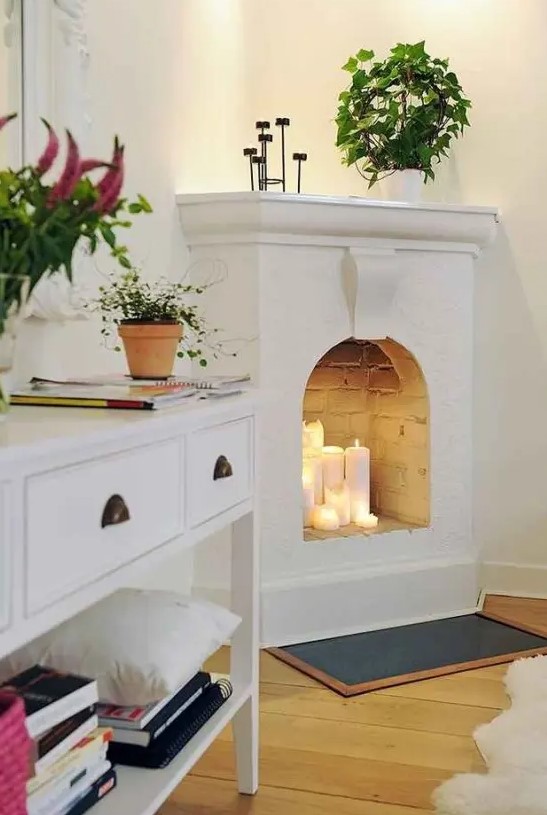 a simple and small white fireplace with pillar candles is a cool idea for a modern space