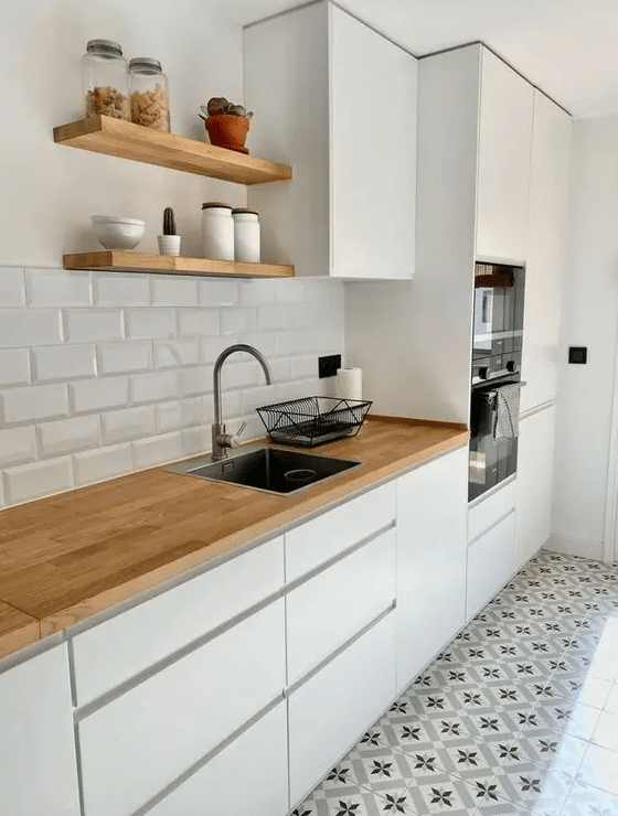 a simple white Scandi kitchen with sleek cabinets, butcherblock countertops and a white subway tile backsplash