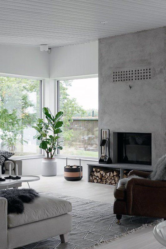 a stylish contemporary living room with a concrete fireplace with firewood storage and lots of natural light