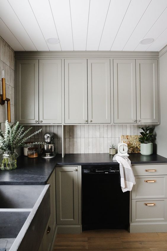 a stylish dove grey kitchen with neutral stacked tiles on the backsplash and black countertops is an ultimate example of farmhouse style