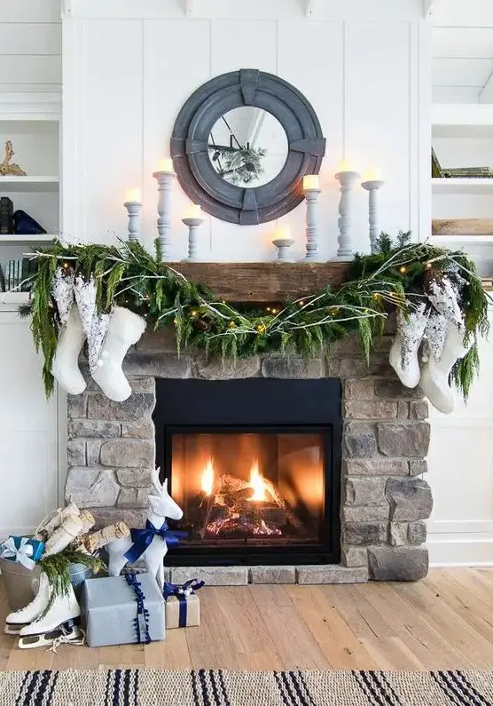 a stylish fireplace clad with stone decorated with evergreens, stockings and some candles is amazing for a farmhouse space