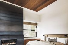 a sytlish contemporary bedroom with a large built-in fireplace surrounded with grey steel sheets for a slight chalet feel