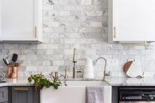 a two toned farmhouse kitchen in white and grey, with a marble subway tile backsplash and touches of various metals