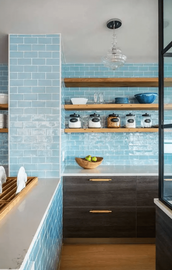 a unique kitchen clad with light blue subway tiles all over the walls, dark cabinets and open shelves is a cool idea