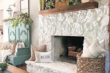 a vintage farmhouse living room with a white stone fireplace, a stained mantel, blooms and baskets is very welcoming