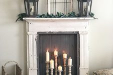 a vintage fireplace with a black screen and candles in wooden candle holders