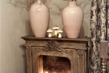 a vintage fireplace with moss, mushrooms and tall and thin candles, branches in blush vases on the mantel