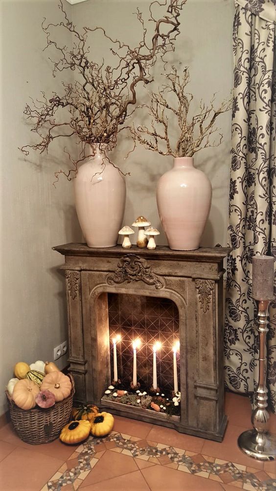 a vintage fireplace with moss, mushrooms and tall and thin candles, branches in blush vases on the mantel