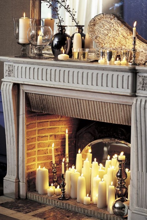 a vintage fireplace with pillar and tall and thin candles and with vintage candle holders in it