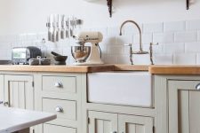 a vintage light green kitchen with large scale subway tiles, wooden countertops and a traditional dining set with benches for a countryside feel