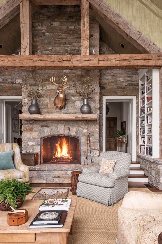 a welcoming cabin living room with stone walls and a fireplace, wooden beams, a jute rug and vintage furniture