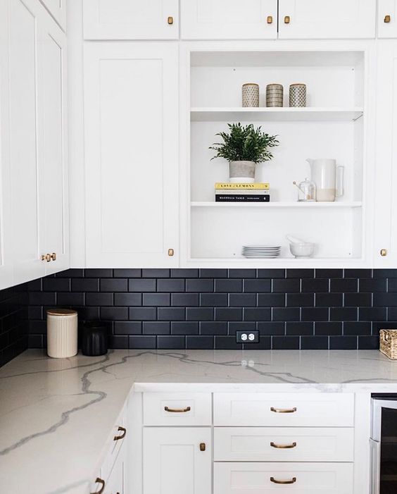 a white modern farmhouse kitchen with white countertops and a black matte subway tile backsplash for a contrast