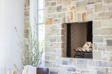 a whole wall clad with stone and with a built-in fireplace is a cool solution for a rustic home, it will add texture and interest to the space