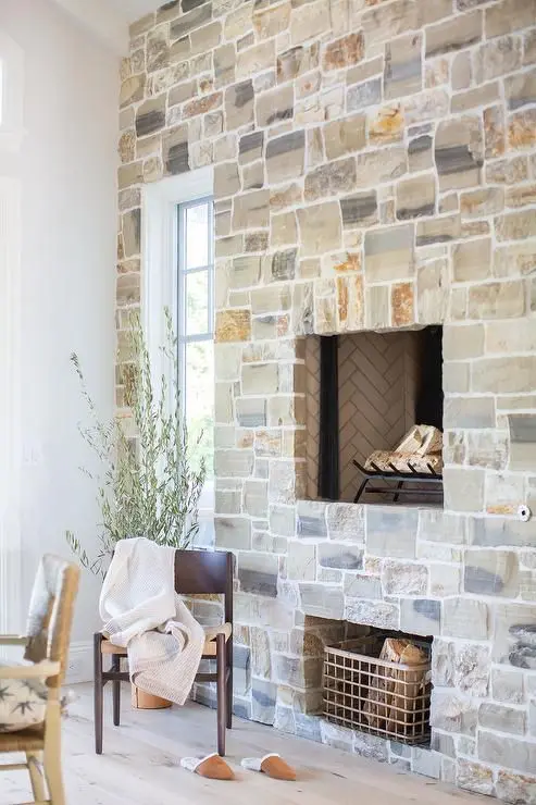 a whole wall clad with stone and with a built-in fireplace is a cool solution for a rustic home, it will add texture and interest to the space