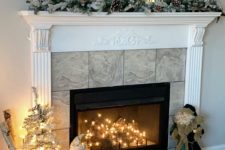 a winter fireplace with logs and lights inside, with a Christmas styled mantel and some branches