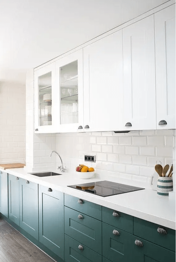 an elegant kitchen with white and dark green cabinets, white stone countertops, a white subway tile backsplash