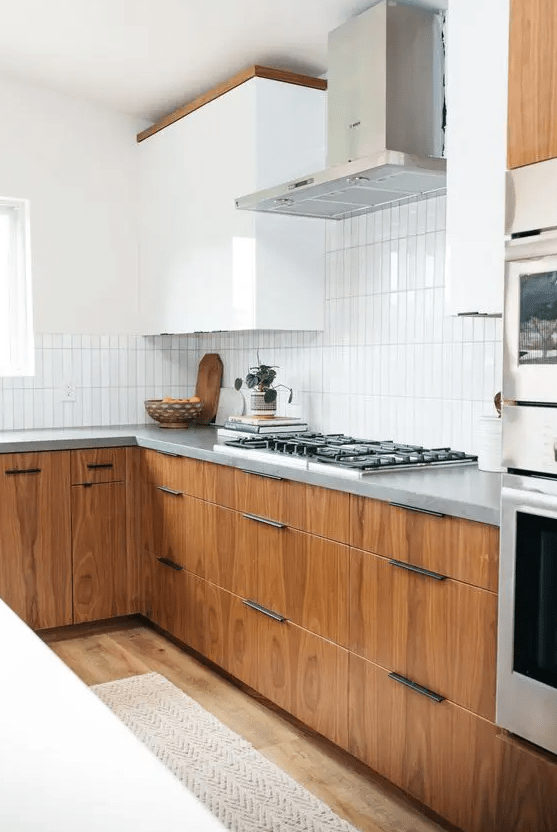 an elegant mid-century modern kitchen with white and stained cabinets, grey countertops and a white stacked tile backsplash