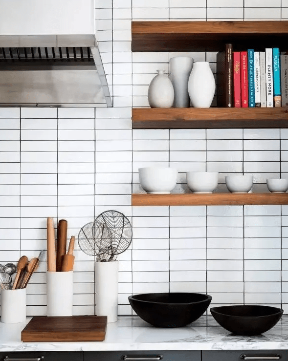 an elegant modern farmhouse kitchen with white stacked skinny tiles on the backsplash, open shelves, black cabinetry and white marble countertops