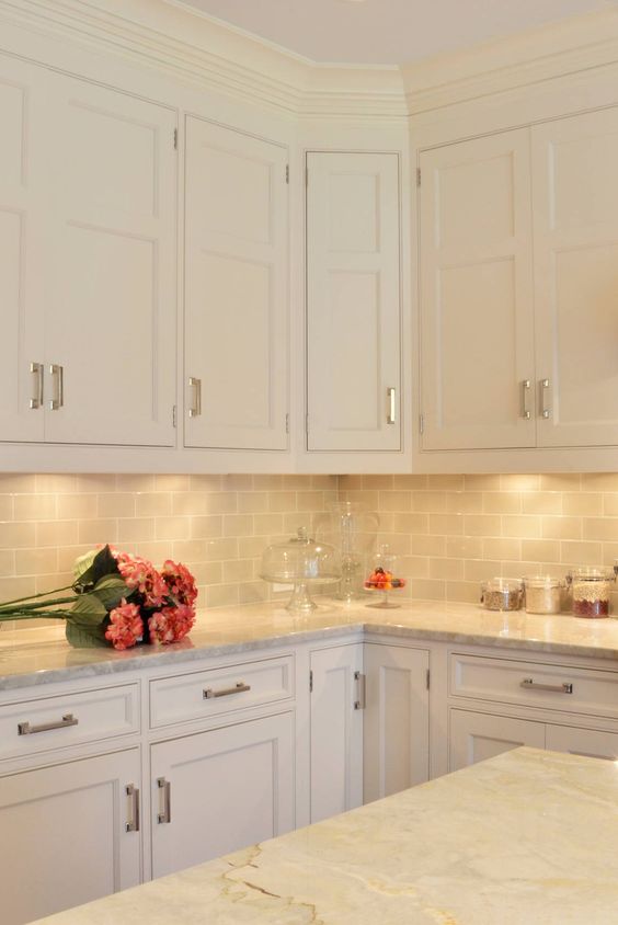 an elegant neutral kitchen with creamy cabinets, a grey subway tile backsplash and grey countertops