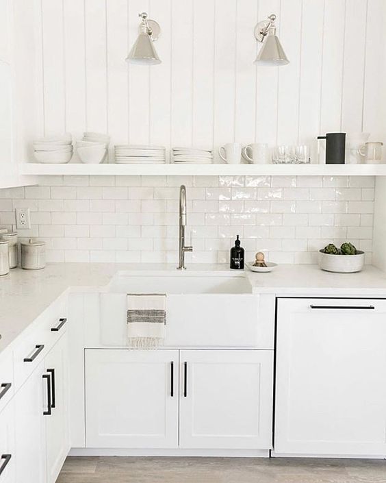 an ethereal white kitchen with shaker cabinets, white countertops, an open shelf and black fixtures