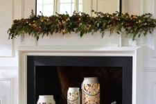 beautiful white snowflake candle lanterns with candles, pinecones and fir branches for a holiday-ready fireplace