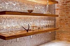 copper penny tiles perfectly pair with wooden shelves with lights and give much color to the space