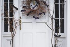natural pumpkins, branches, lot sof bats and a twig wreath make this Halloween porch feel very rustic and natural