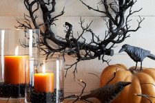 rustic Halloween decor with a scary vine wreath, blackbirds, rust-colored candles in black beans and lights