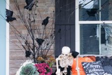 rustic outdoor Halloween decor with blackbirds, bright blooms and veggies, pumpkins, skeletons and branches