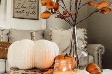02 cozy rustic fall decor with faux pumpkins including a crochet one, a candle and dried leaves on branches
