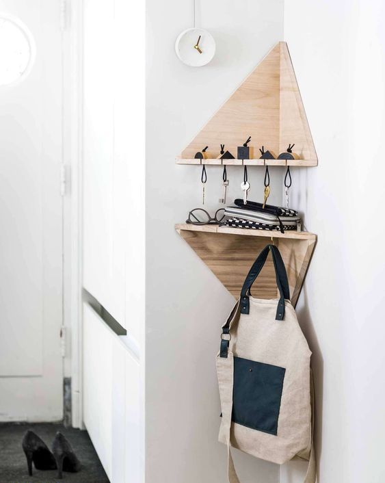 tiny geometric corner shelves with a key holder and some hooks are a great idea for a tiny entryway
