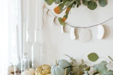03 a modern rustic mantel with eucalyptus, natural pumpkins, a greenery wreath over them and a moon phase hanging