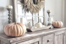 04 neutral rustic fall decor with chalk painted pumpkins, a dried husk wreath, candles and white pumpkins in a bowl