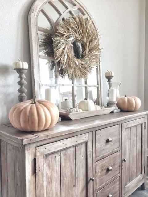 neutral rustic fall decor with chalk painted pumpkins, a dried husk wreath, candles and white pumpkins in a bowl