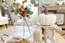 07 a simple and chic fall arrangement of a candle, wooden beads, faux pumpkins and a billy ball and greenery bouquet