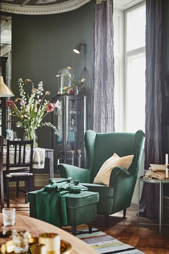 a refined vintage inspired space with a hunter green wingback chair and a footrest by the window to read comfortably here